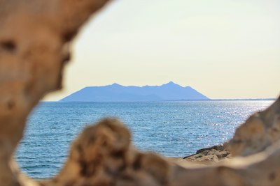 Distant island across the sea framed by natural rock formations.