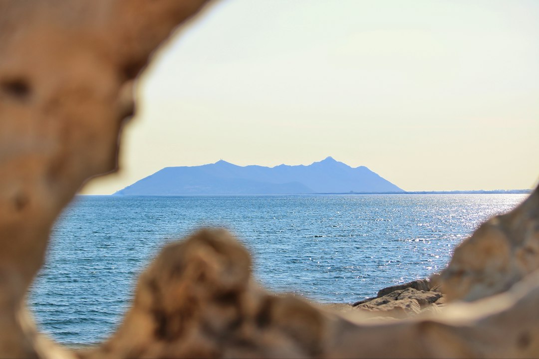 Distant island across the sea framed by natural rock formations.