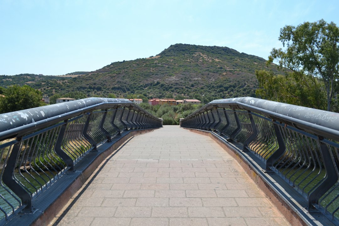 A modern pedestrian bridge leads to a green hill